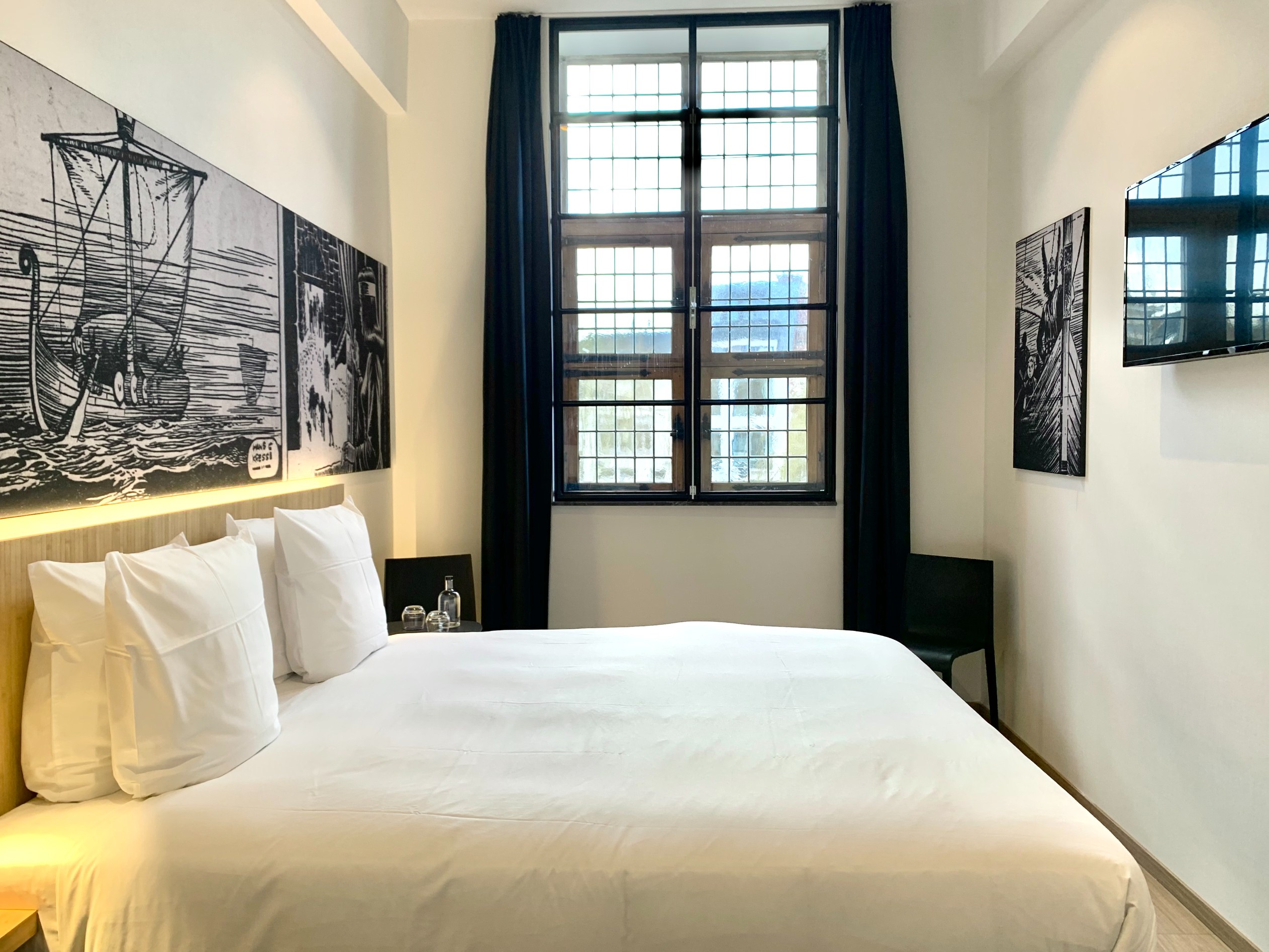 Cosy View room with white linens and a black-framed window
